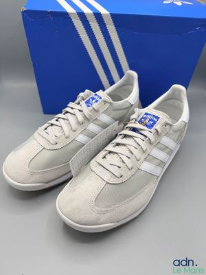 une paire de baskets adidas blanches à rayures bleues et blanches