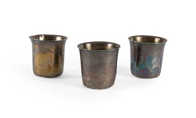 trois petites tasses en métal posées les unes à côté des autres sur une surface blanche