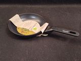 a frying pan with a piece of paper sticking out of it