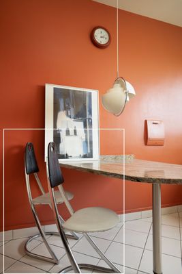 une table avec une chaise et une horloge accrochée au mur