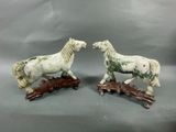 two figurines of horses standing on a wooden base