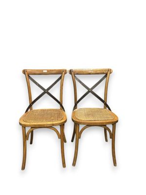 a pair of wooden chairs with cross back and cane seats