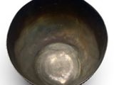 a metal bowl that is sitting on a white surface