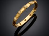 a yellow gold bang bracelet with diamonds on a black surface