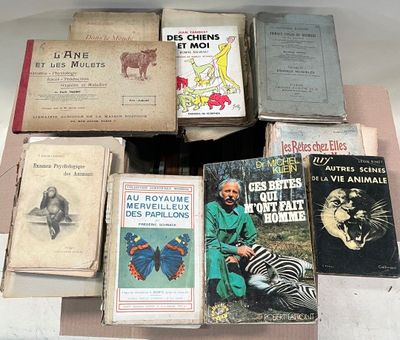 a lot of books on a table with a man sitting next to them