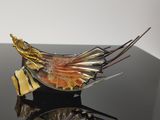une sculpture en verre représentant un oiseau sur un fond noir