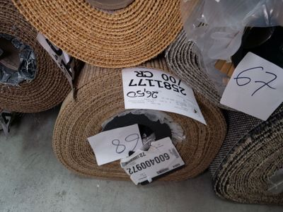 many rolls of carpet on the floor with tags on them