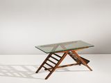 une table en verre avec des pieds en bois et un plateau en verre, posée sur un sol blanc
