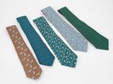 quatre cravates de couleurs différentes sont alignées sur une surface blanche