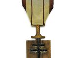 une vieille médaille avec une croix au recto et un ruban au verso