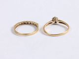 two gold rings with diamonds on them sitting next to each other