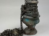 a silver vase with chains around it on a white surface