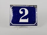 une vieille plaque de numéro de maison bleue et blanche sur laquelle figure le chiffre 2