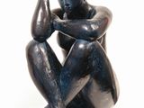 statue of a man sitting on a pedestal with his hand on his head