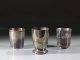trois coupes en argent posées sur une table, sur fond noir