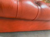 a red leather couch that is sitting on the floor