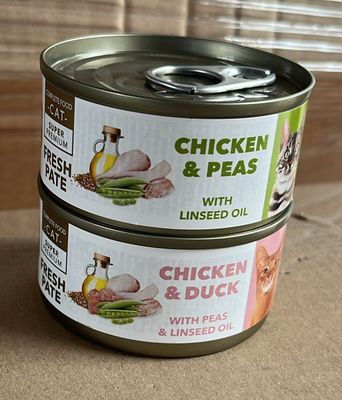Deux boîtes de poulet aux petits pois à l'huile de lin sont posées sur une table