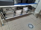 many trays of food sitting on a shelf in the kitchen