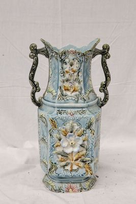 un vase bleu avec des fleurs posé sur une surface blanche