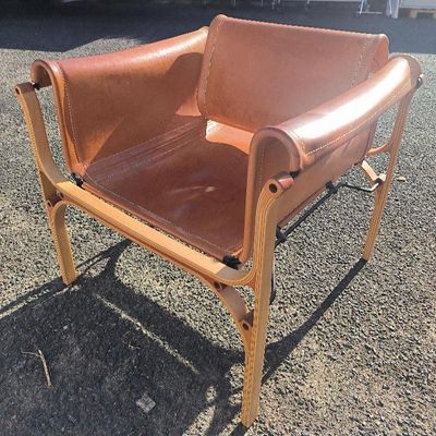 un fauteuil en cuir marron posé sur le gravier