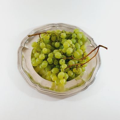 a bowl of green grapes sitting on a white table