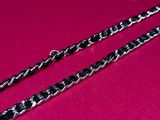 a pair of black and silver chains on a pink surface