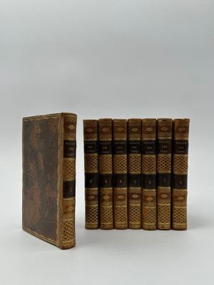 Trois livres sont posés sur une surface blanche ; l'un d'entre eux est ouvert.