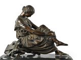 bronze statue of a woman reading a book on a marble base