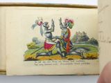 a hand holding a book with a picture of two knights on it