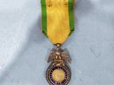 an image of a medal with a gold eagle and a green ribbon