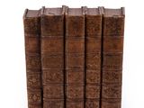 several old books stacked on top of each other on a white surface