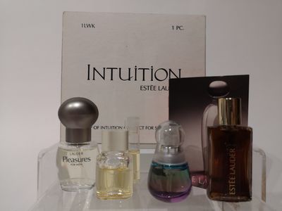 Des flacons de parfum sont posés sur une étagère transparente, à côté d'un livre