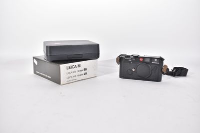 a black camera sitting on top of a box on a white surface