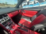 l'intérieur d'une voiture avec des sièges en cuir rouge et des garnitures en cuir noir