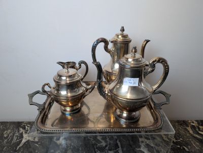 a silver tea set on a tray on a marble table