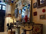 une pièce avec un miroir, une chaise, une table et des tableaux accrochés au mur