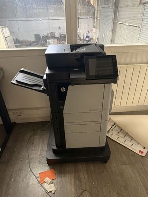 une imprimante noir et blanc posée sur un support devant une fenêtre