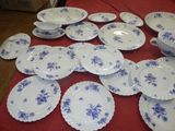 many plates and bowls on a table with a red table cloth