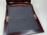 an old wooden box with a black cloth inside on a white surface