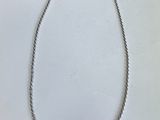 gros plan d'un collier en argent sur une surface blanche