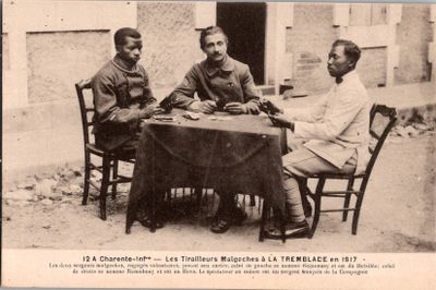 trois hommes assis à une table devant un immeuble