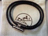 un gros plan sur un bracelet en cuir noir muni d'un fermoir en argent