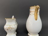 two white and gold vases sitting next to each other on a table