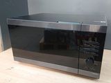 un four à micro-ondes noir posé sur une table en bois