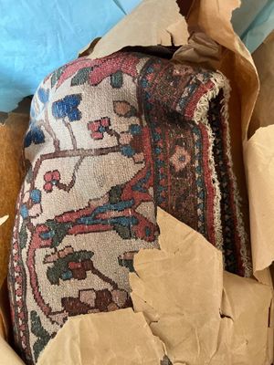 a cardboard box with some old rugs in it