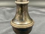an antique brass vase on a gray cloth with a black background
