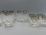 six verres aux bords argentés sont alignés sur une surface blanche