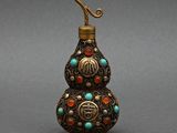 une vieille bouteille en laiton ornée de perles turquoise, rouges et vertes