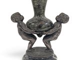 a statue of two people holding a vase on top of a table