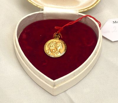 a heart shaped box with a gold medal in it
